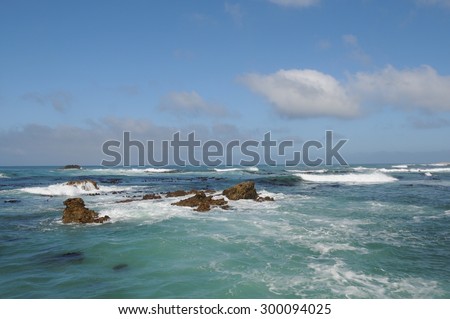 Emerald waves crashing onto rocks near the Cape of Good Hope, South Africa