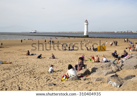 NEW BRIGHTON, UK - 8 AUGUST 2015. New Brighton beach on a hot day in the summer with people and families relaxing, sunbathing and enjoying the weather.