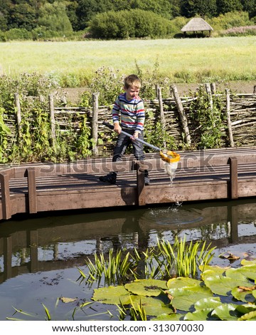 LEEDS, UK - 2 SEPTEMBER 2015. Pond dipping using a net to sample nature present in wildlife pond and identity insects and fish.