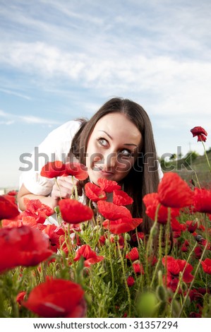 Funny woman smelling poppy flowers