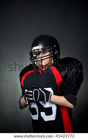 Young boy in football uniform isolated on black