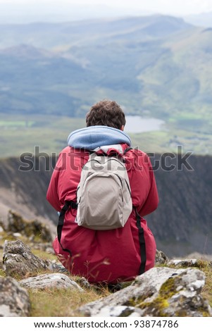Young man sitting looking over mountains