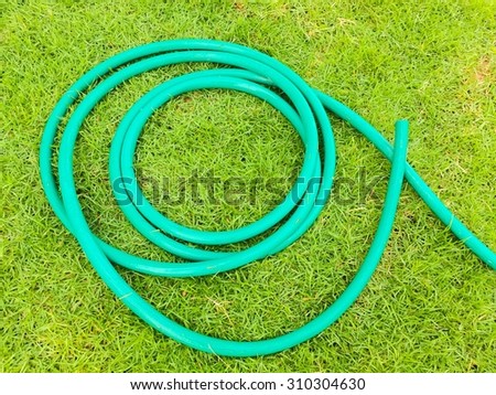 Water hoses lie on the garden grass green field