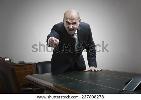 Angry boss behind of office table