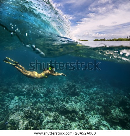 Underwater Sport Postcard. A freediver floating under water surface in ocean. Female model using fins and snork diving with surfing wave.