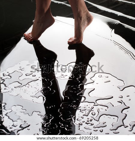 women's graceful smooth legs on wet glass with water drops and mirror of light