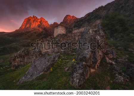 Ingushetia, Land Of Towers And Legends. One Of The Ancient Tower Complexes At The Foot Of Mount Tsey-Loam On The Mountain Pass Of The Same Name.Tsey-Lom Peak At Sunrise.Erzi, North Caucasus, Russia. Stock fotó © 