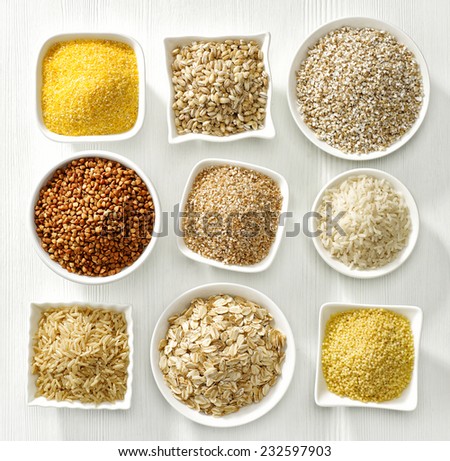 various kinds of cereal grains on white wooden table