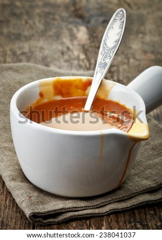 bowl of melted caramel sauce on old wooden table