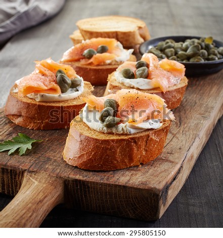 toasted bread slices with cream cheese and smoked salmon on wooden cutting board