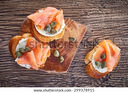 toasted bread with smoked salmon fillet and cream cheese on wooden table, top view