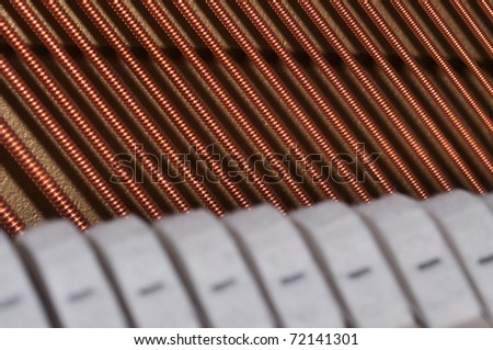 Piano strings in closeup with hammers on foreground