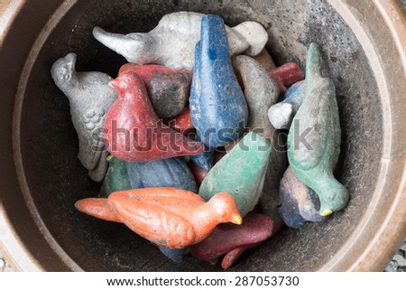 Colorful clay birds in a pot.