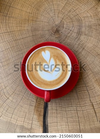 А cup of delicious cappuccino on a wooden table in a bright red cup. Coffee culture. Late art. Сток-фото © 