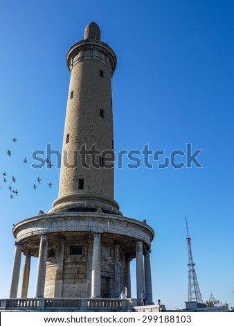 DALIAN, CHINA - 2014: Birds fly around White Jade Mountain Tower in blue sky. Tower\'s construction finished in 1909 after Russo-Japanese War (1904-1905), located in Lushunkou, Dalian.