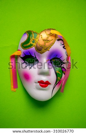 Colorful masquerade face mask on a green background.