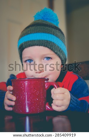 Child drinking hot chocolate from a mug.