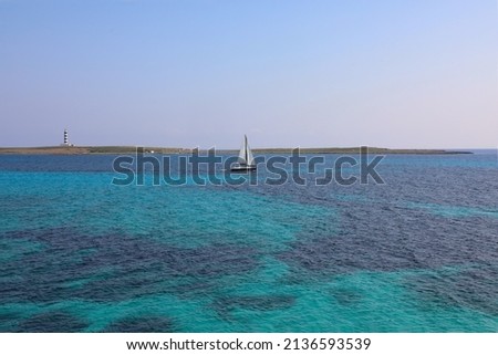Lighthouse of the island of the air, in front of Punta Prima, with a sailboat sailing through turquoise waters Stockfoto © 