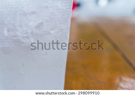 A center cup that have ice-water on left of wood background