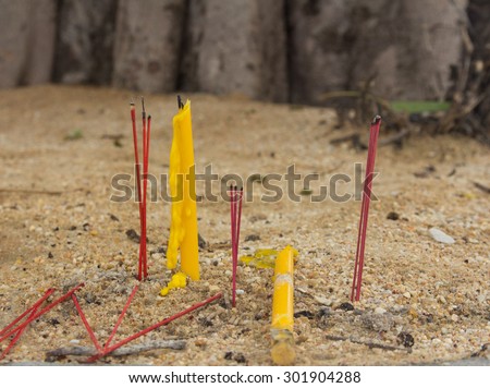 Candles and incense sticks on the sand