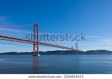 The Tagus River (Rio Tejo) and the iconic suspended bridge (Ponte 25 de Abril), with the Cristo Rei statue in the background - Lisbon, Portugal Foto stock © 