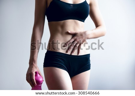 The girl checks her muscles on her stomach after the workout. She has achieved the result she wanted