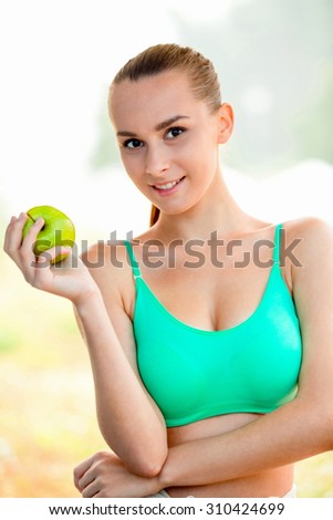 The sport girl eats only healthy food. She loves to eat apples.