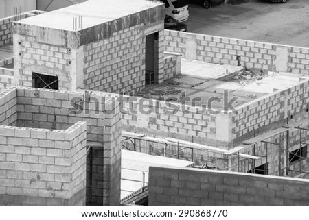 Black and white image of half built villas showing internal walls and scaffolding and rebar. Taken in Janabiya, Bahrain.