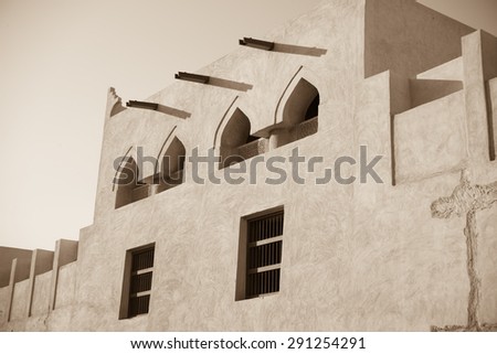 Exterior adobe wall of Isa bin Ali House, Muharraq, Bahrain showing arched windows, wooden window frames and water guttering.