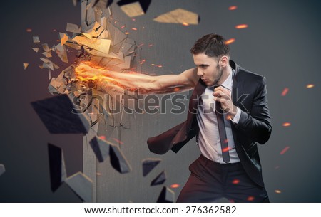 An angry businessman hitting concrete wall