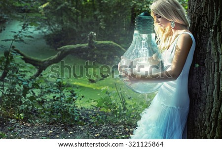 Art photo - stunning blonde beauty holding a big lightbulb