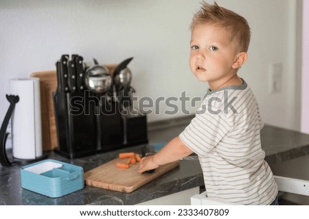Anonymous boy cutting carrot in kitchen