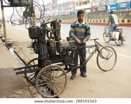 Chandigarh, India,Dec 20, 2012.A man stands by his tricycle on the side of the road holding some electrical cables which are connected to an electric generator mounted in the back of his vehicle.
