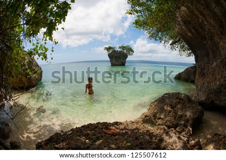 Girl swimming in the sea on a pacific island with small island in the back