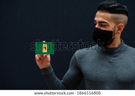 Egyptian man in gray turtleneck and black face protect mask show Sohag flag isolated background. Governorates of Egypt coronavirus concept. Imagine de stoc © 