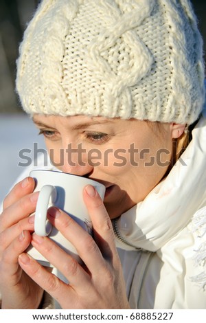 portrait of adult women in white, with mug in his hands, bright sunny frosty day