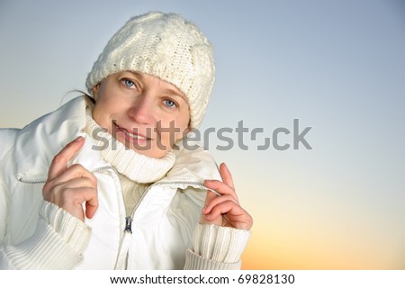 Blue-eyed woman in white on the sunset  sky background. winter.