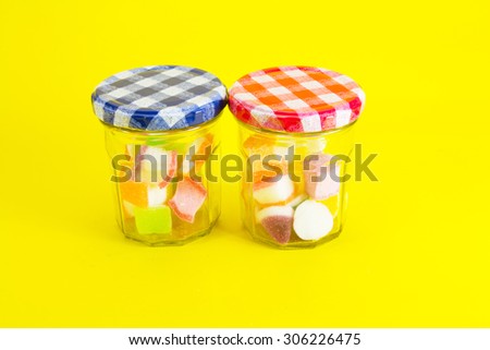 Colorful jelly candies in jar on yellow background