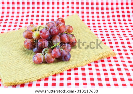 Ripe red grape on red and white textured plaid gingham table