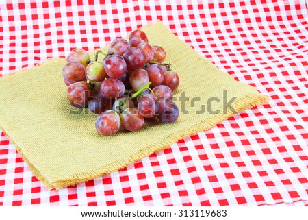 Ripe red grape on red and white textured plaid gingham table