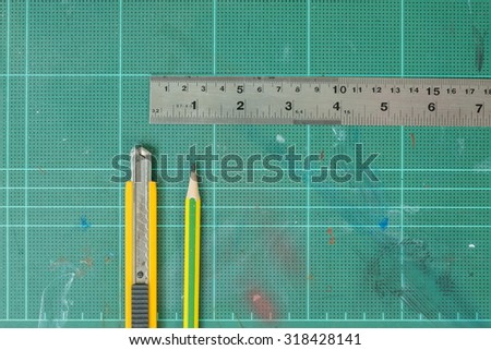 Cutter , wood pencil and ruler on old green rubber pad background