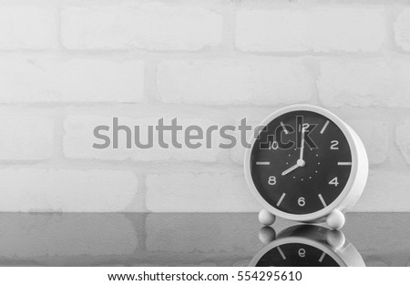 Closeup black and white alarm clock for decorate in 8 o'clock on black glass table and white brick wall textured background in black and white tone with copy space Foto stock © 