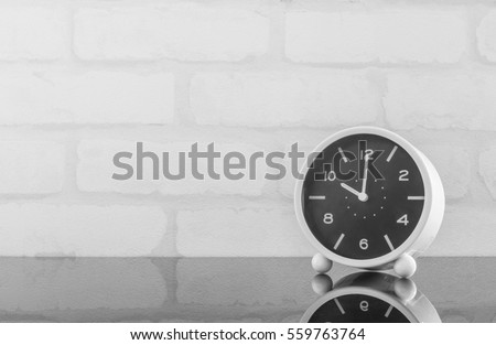 Closeup black and white alarm clock for decorate in 10 o'clock on black glass table and white brick wall textured background in black and white tone with copy space Foto stock © 