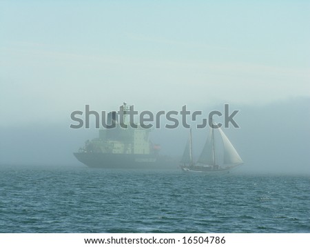 A sail boat, and container ship in the fog, at Halifax harbor, Atlantic Canada.