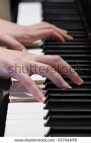 Detail of woman hands playing piano. Closeup of grand piano keyboard.