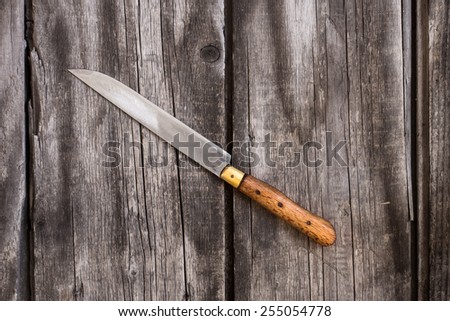 top view angled shot of a vintage single large knife on rustic wooden boards underneath