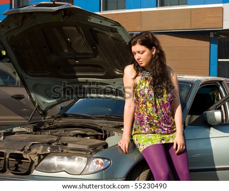 Young woman with her broken car. The girl is sad. Vehicle Breakdown. Beautiful girl thinking about what to do with car breakdown