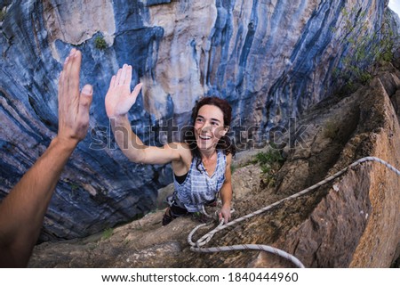 A woman is climbing in Turkey, Turkish woman climbs the rock, Extreme hobby, Overcoming a difficult climbing route, Overcoming the fear of heights, Emotional girl gives five to a friend.