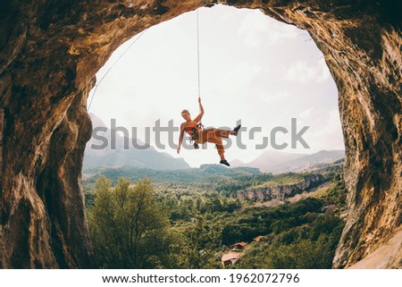 Rock climber hanging on a rope. A woman climbs a rock in the shape of an arch. The girl climbs in the cave. Climbing rope for belaying. Rock climbing in Turkey .