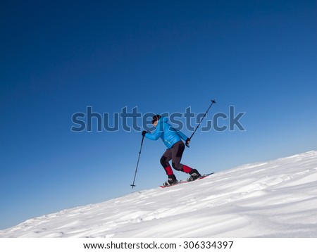 The man jumps in snowshoes in the mountains in the snow.
